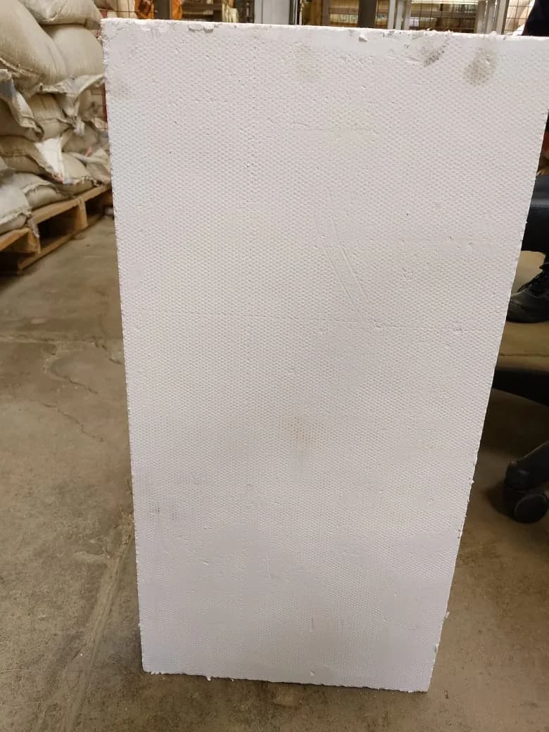 Rigid white high-temperature insulation board standing on a workshop floor