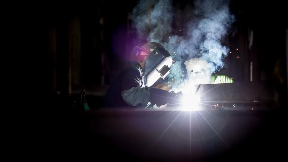 Welder striking an arc in a workshop